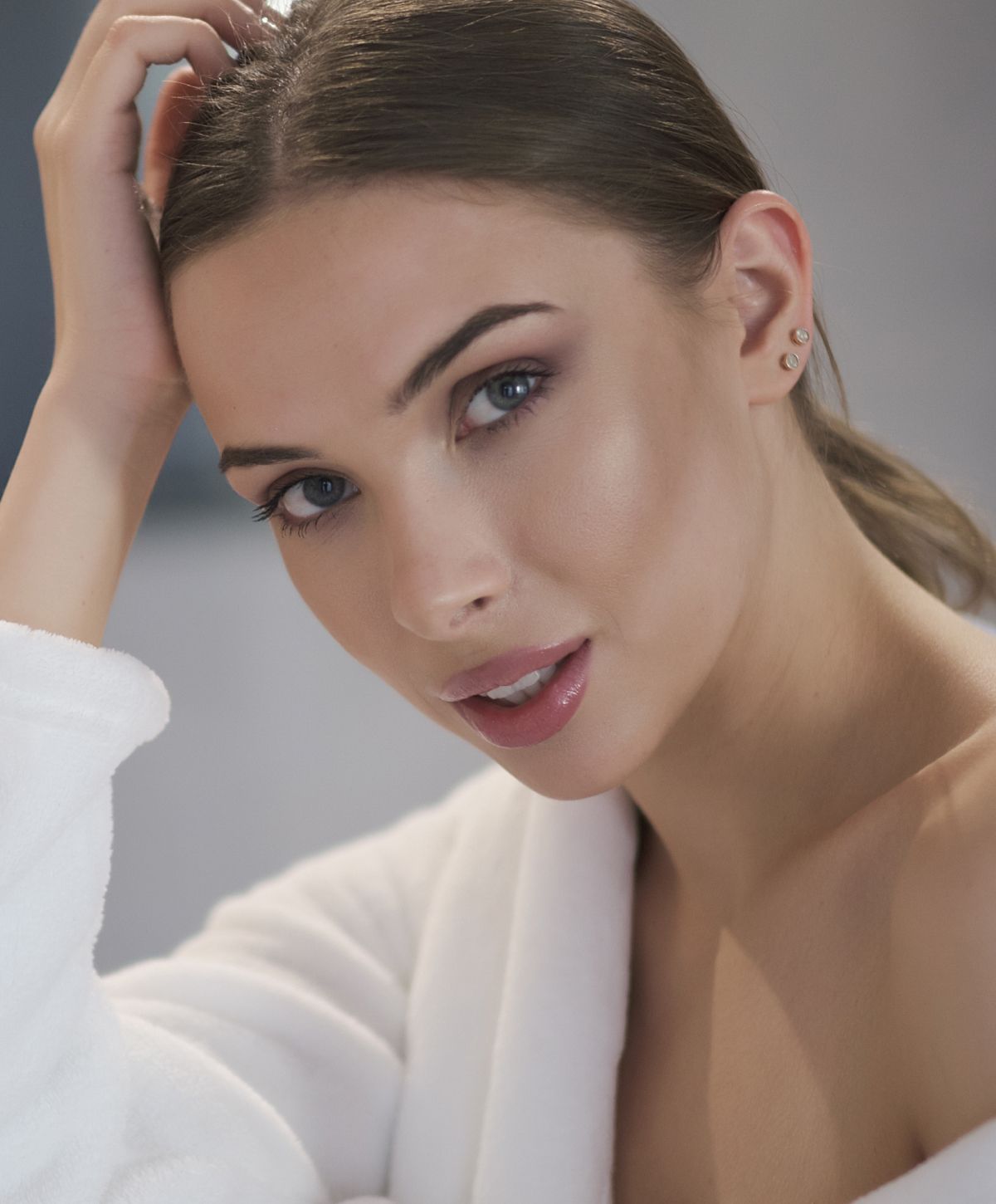 sculptra patient model in a white robe resting her head against her palm